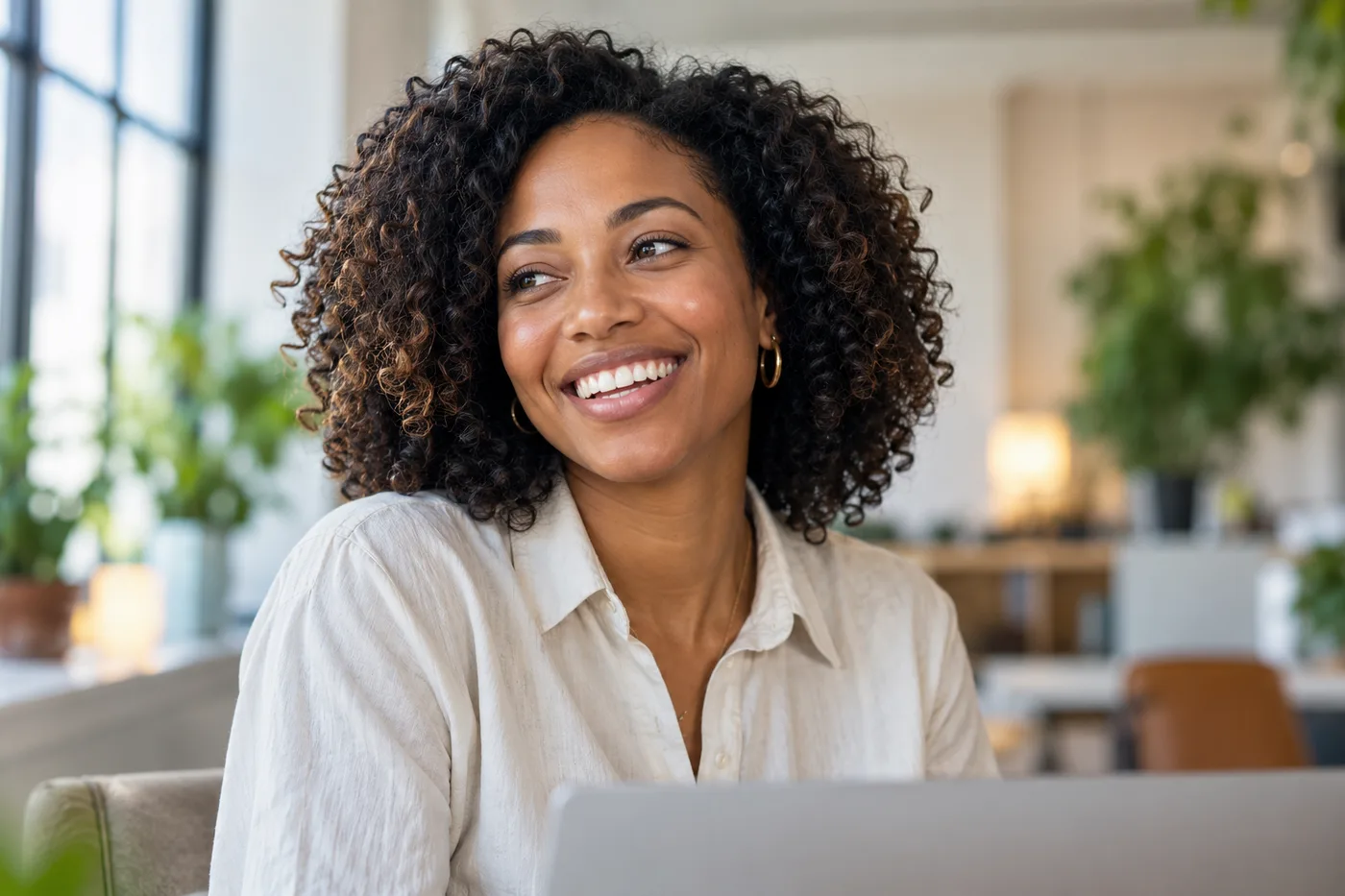 A woman smiling while working at a laptop
